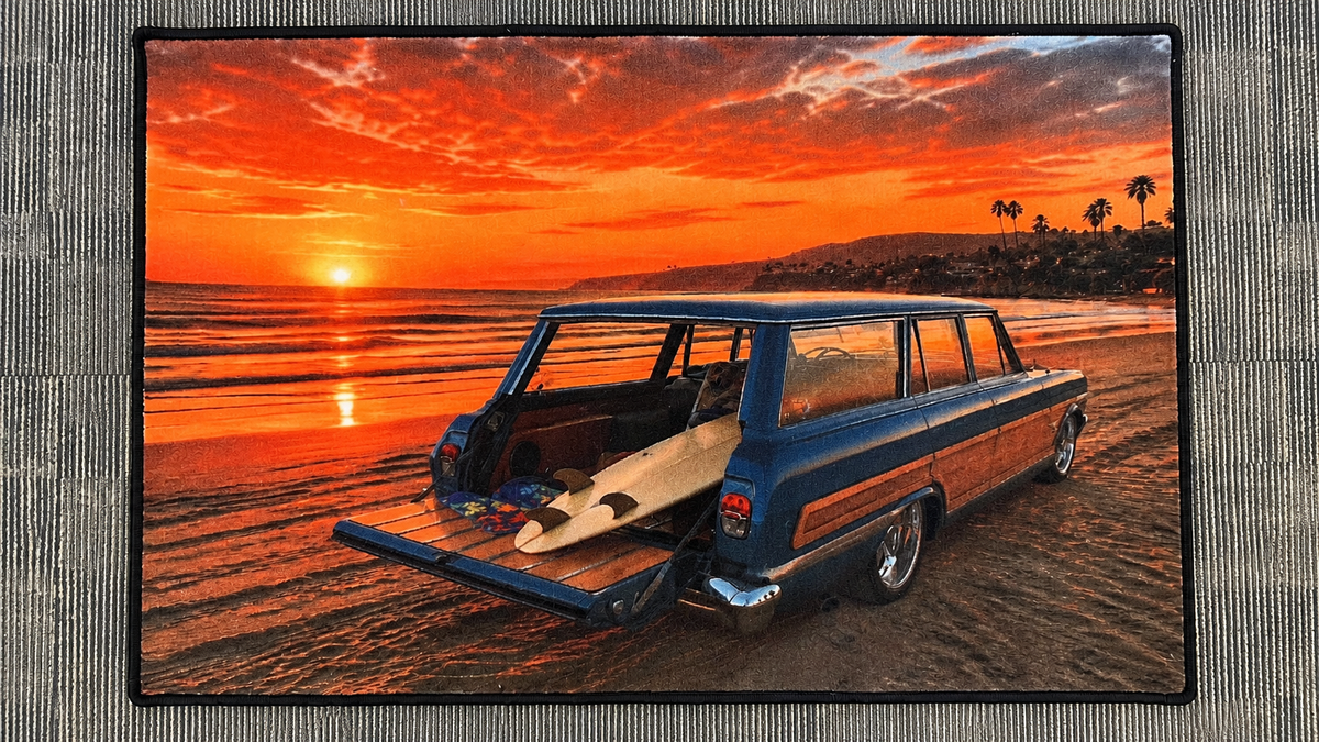 Rectangular custom rug depicting a wood-panel station wagon with an open tailgate and surfboards beside a beach at sunset.